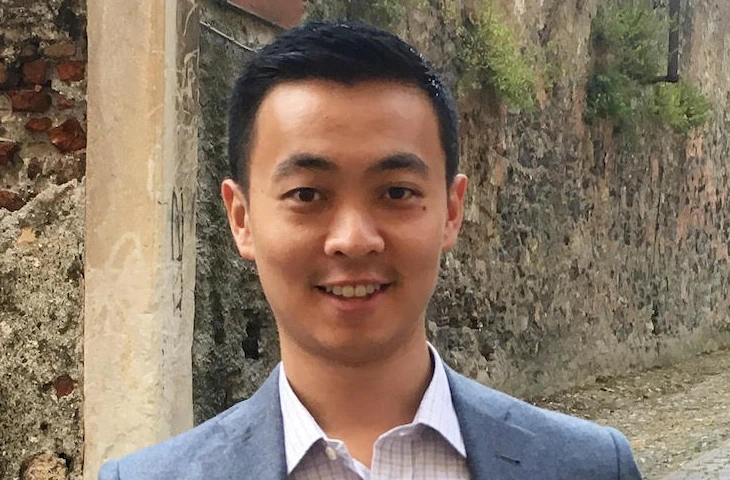 Victor Wong smiling outdoors in a blazer and collared shirt