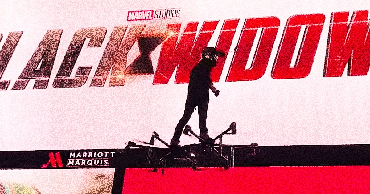 Hunter Kowald riding a large drone-like flying platform in front of a Black Widow movie billboard