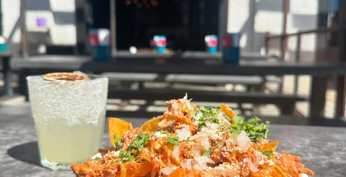 Outdoor patio dining at a Nashville restaurant with drinks and nachos on a table