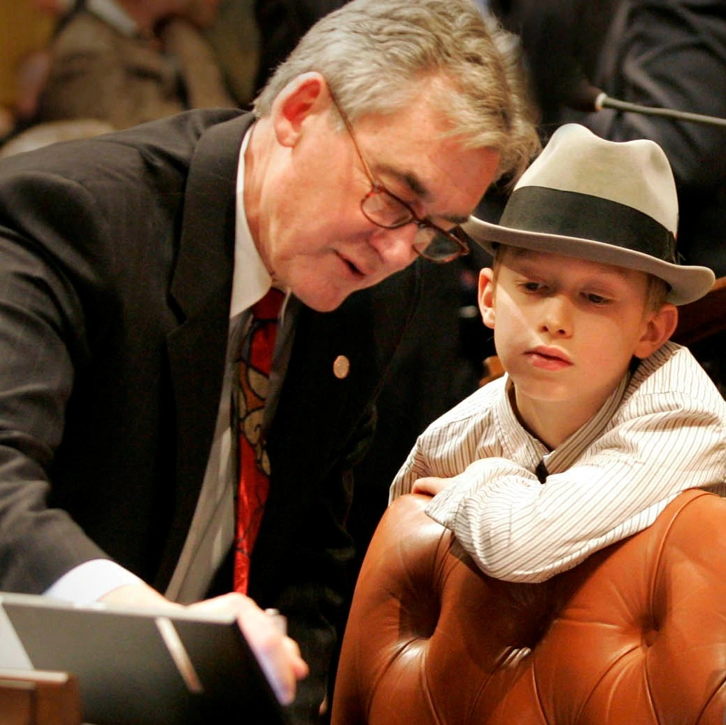 Mark Meadows speaking with a young boy while seated in a chamber