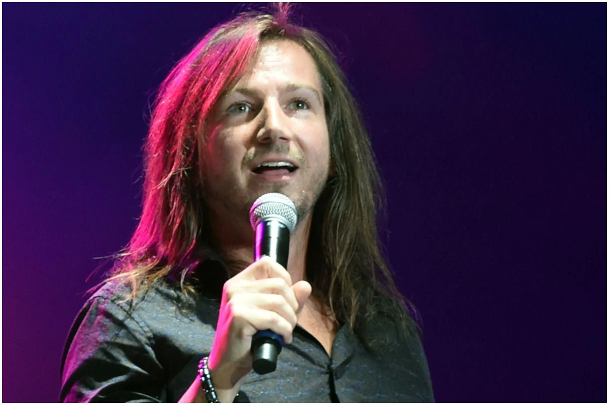 Darren Knight performing on stage with a microphone