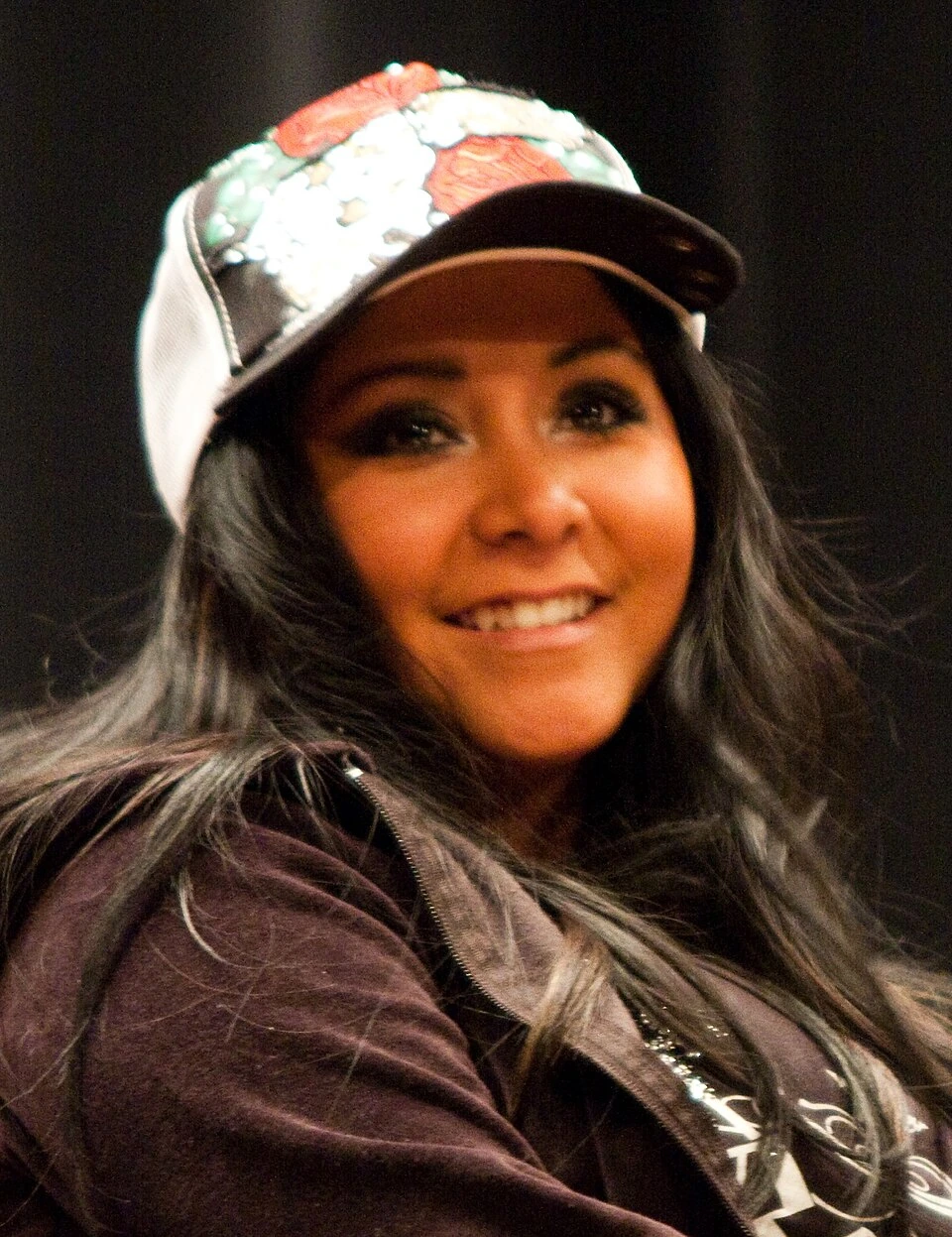 Nicole Polizzi smiling in a close-up portrait wearing a patterned cap