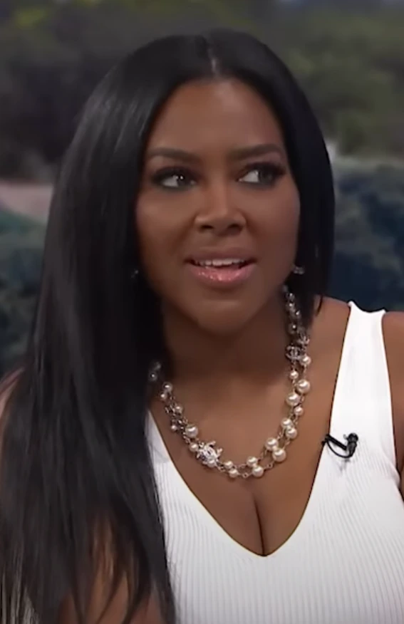 Kenya Moore in a studio portrait wearing a white top and necklace