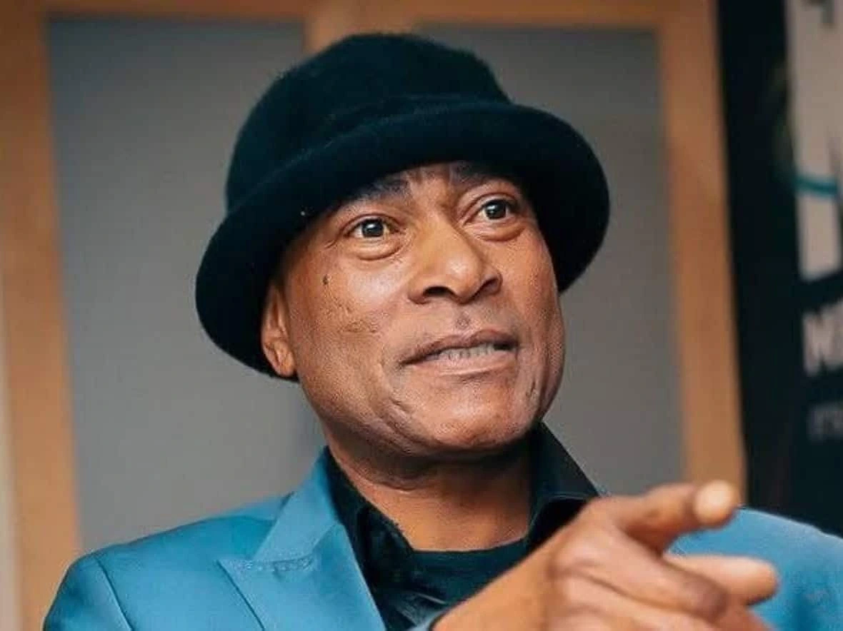 Portrait of South African kwaito artist Victor Bogopane, known as Doc Shebeleza, wearing a black hat and blue jacket.