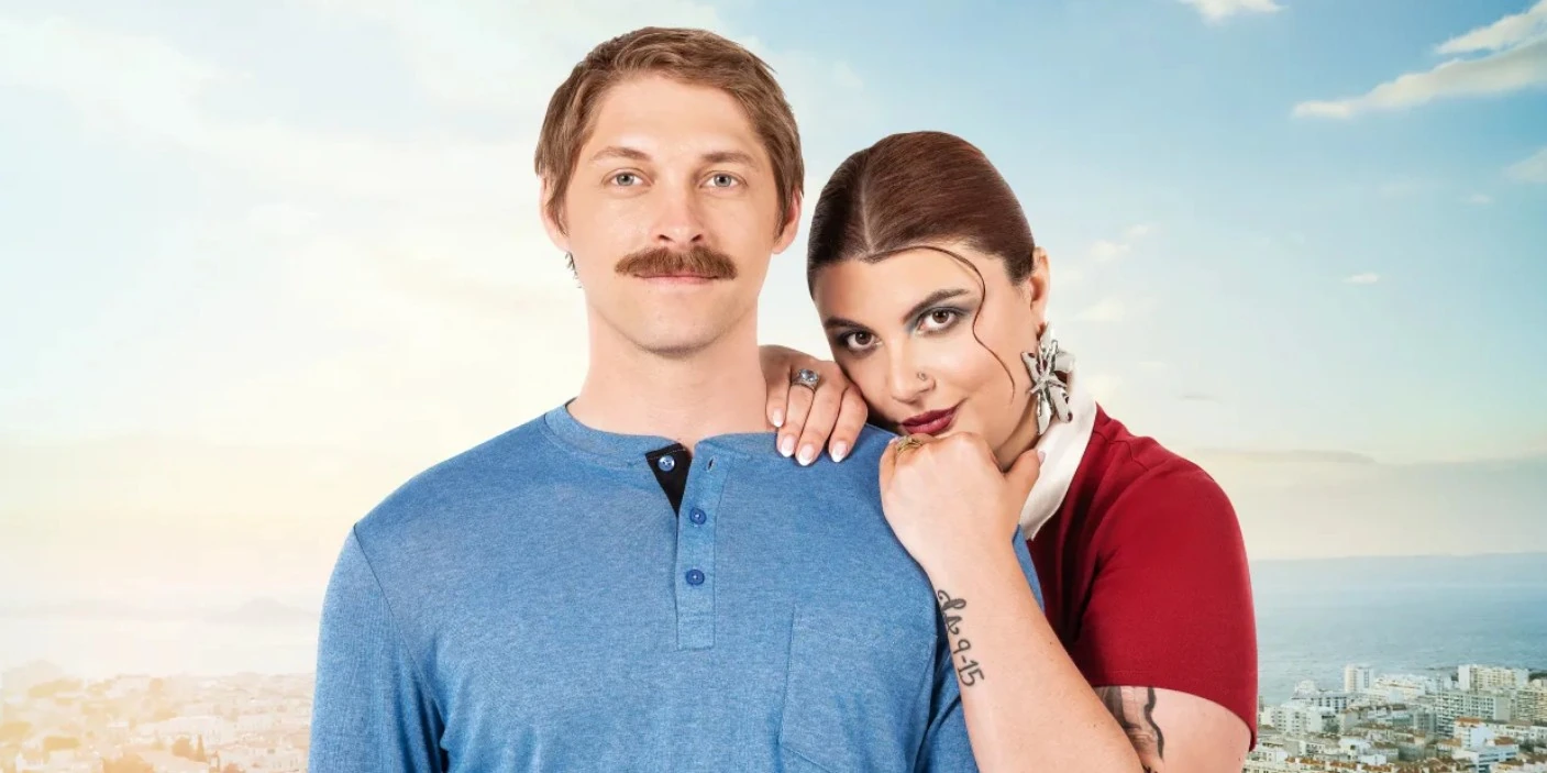 Manon Berryman posing with Anthony Berryman against a scenic sky and city backdrop