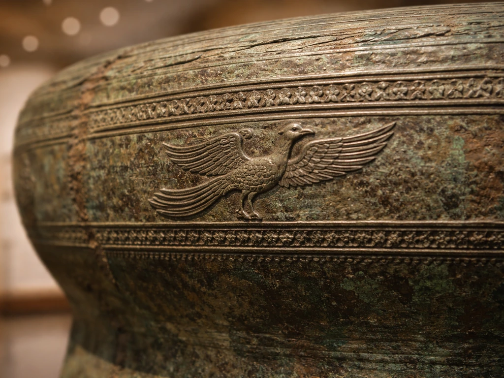 Close-up of an ancient Đông Sơn drum fragment showing the Lạc bird motif in relief.