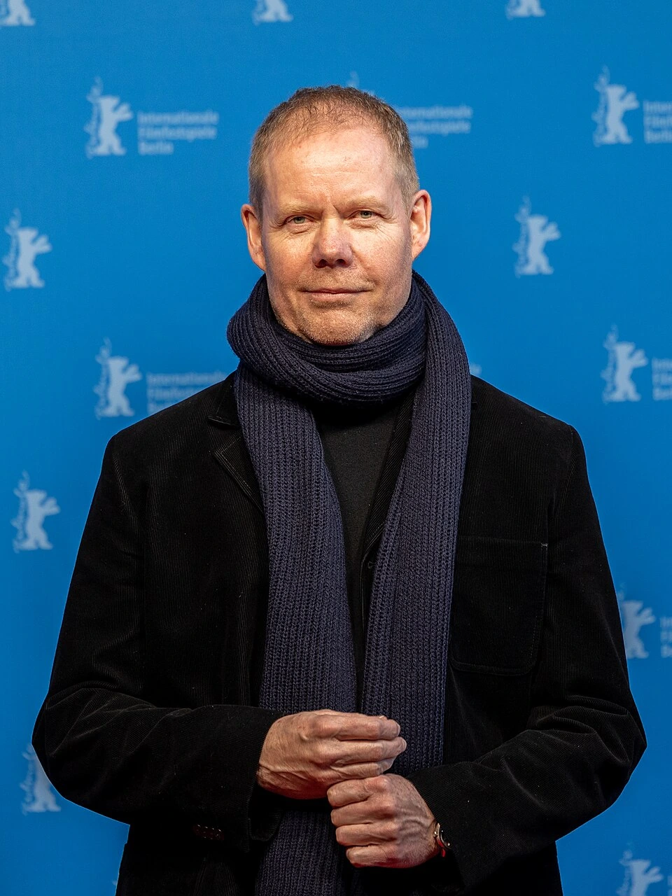 Max Richter at the Berlin International Film Festival, standing in front of a blue backdrop and wearing a dark coat and