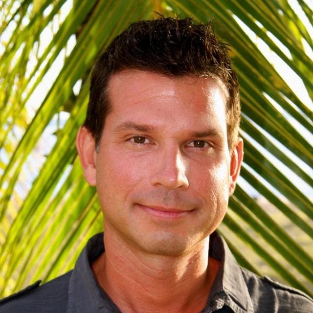 Portrait of Alberto Riehl outdoors in front of palm leaves
