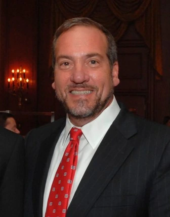 Portrait of Yechiel Eckstein in a suit and red tie smiling at an event
