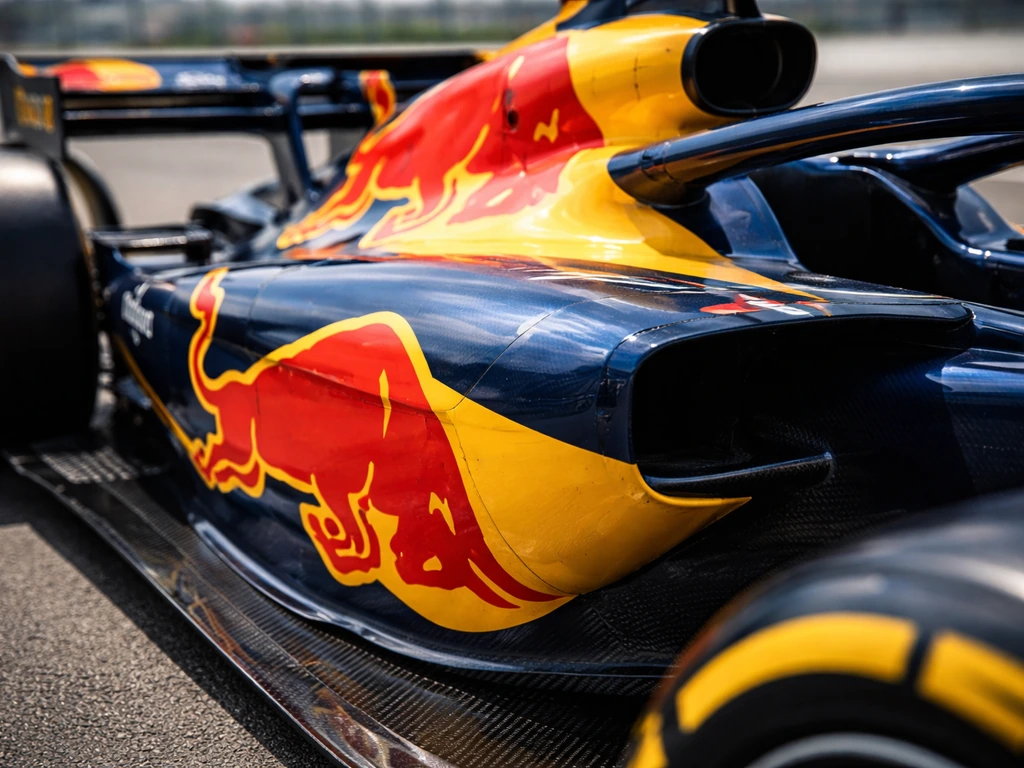 Close-up of a race car’s yellow-and-blue sponsor branding on the body, sharp details, minimal background.