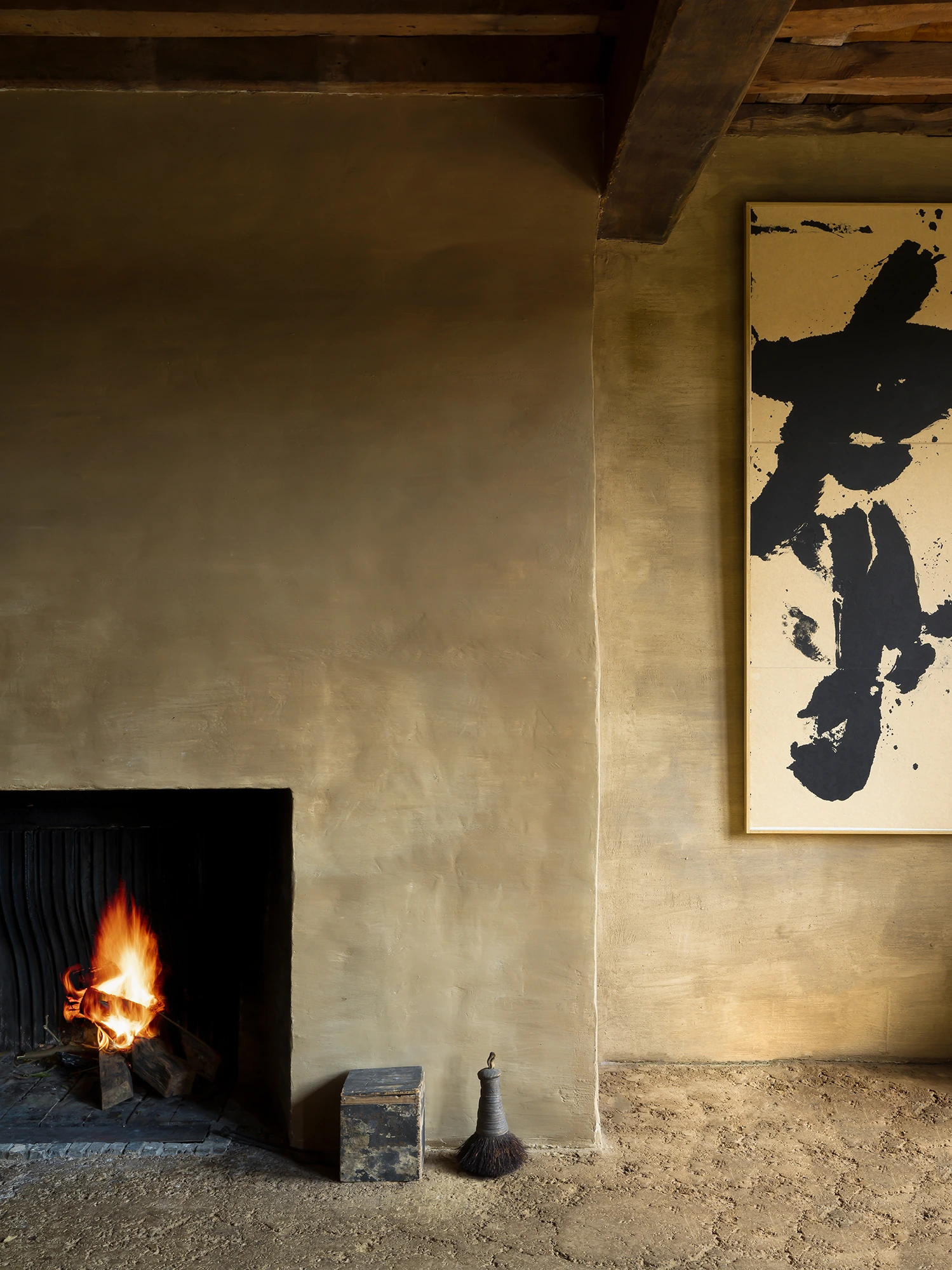 Interior photograph of an Axel Vervoordt-designed room with a fireplace and artwork on the wall