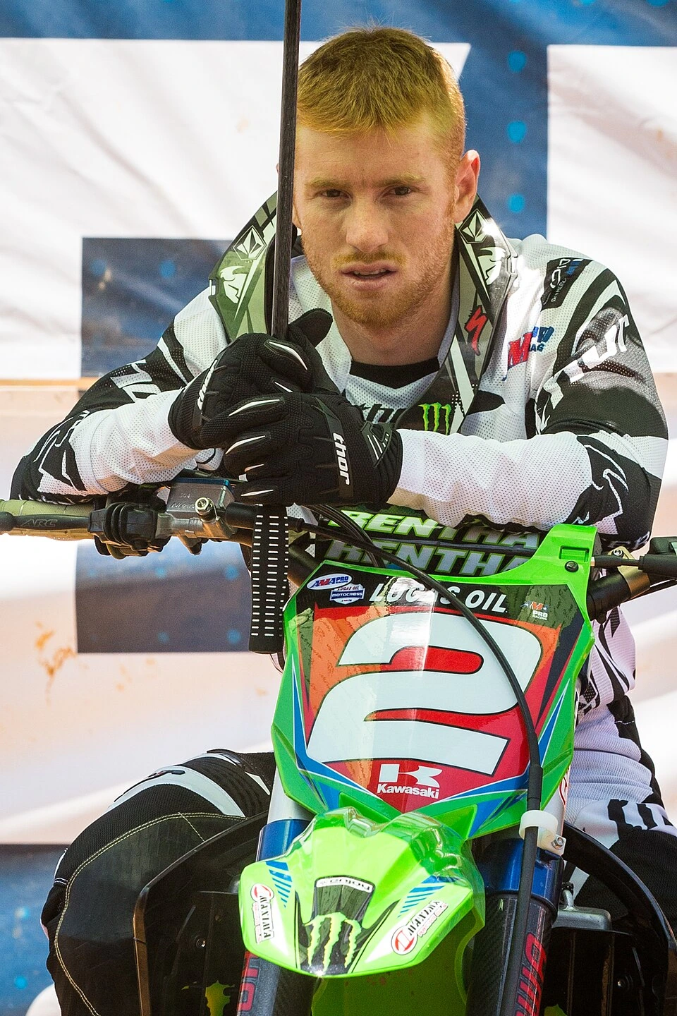 Ryan Villopoto seated on a green Kawasaki motocross bike, wearing racing gear and looking toward the camera.