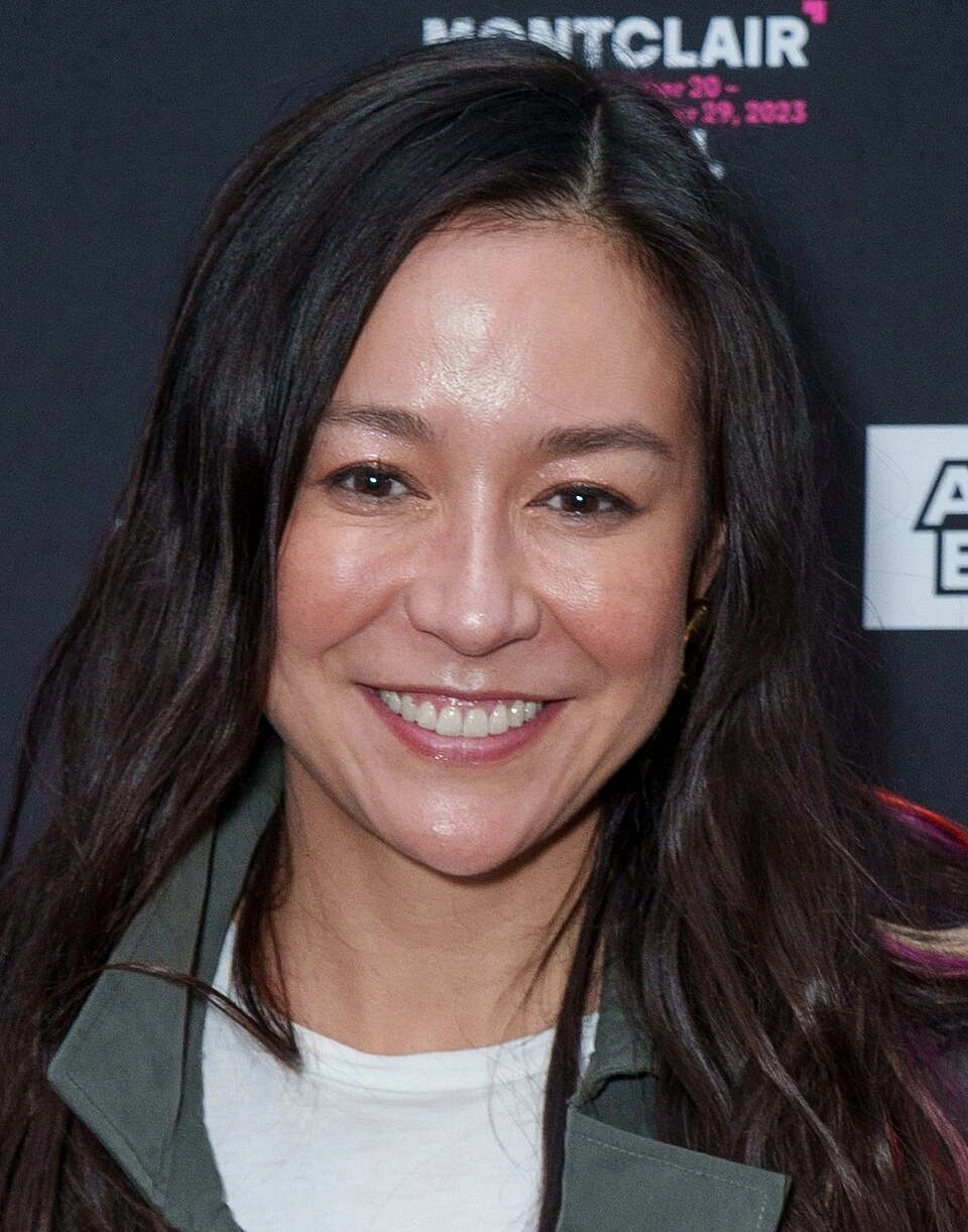 Elizabeth Chai Vasarhelyi smiling at an event backdrop