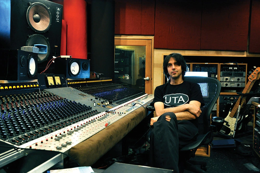 Eric Valentine seated in a recording studio beside a large mixing console