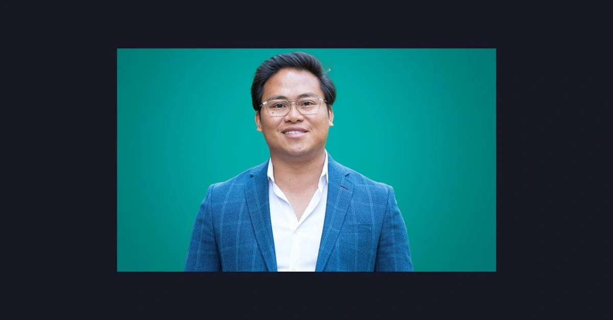 Portrait photo of Chris Steven Villanueva, DMD, founder and CEO of MB2 Dental, wearing a blue blazer against a teal back
