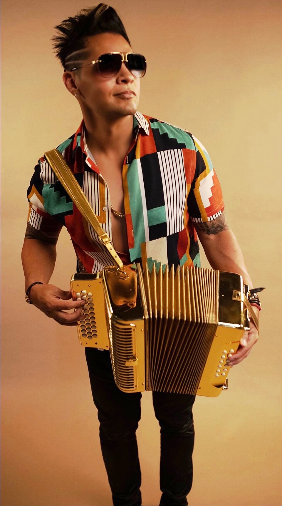Nick Villarreal standing with an accordion against a plain background