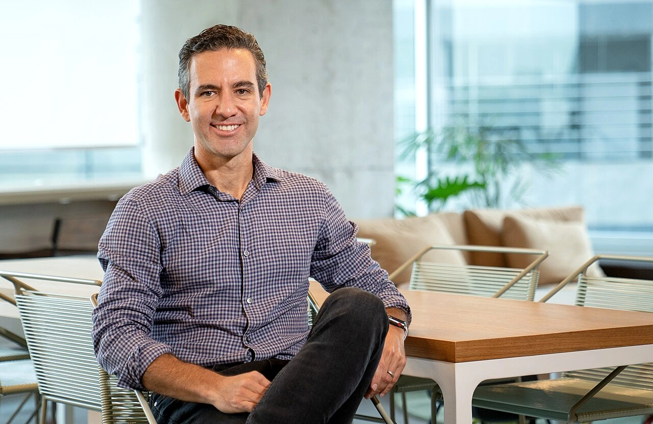 David Vélez sitting in a modern office setting, smiling at the camera.
