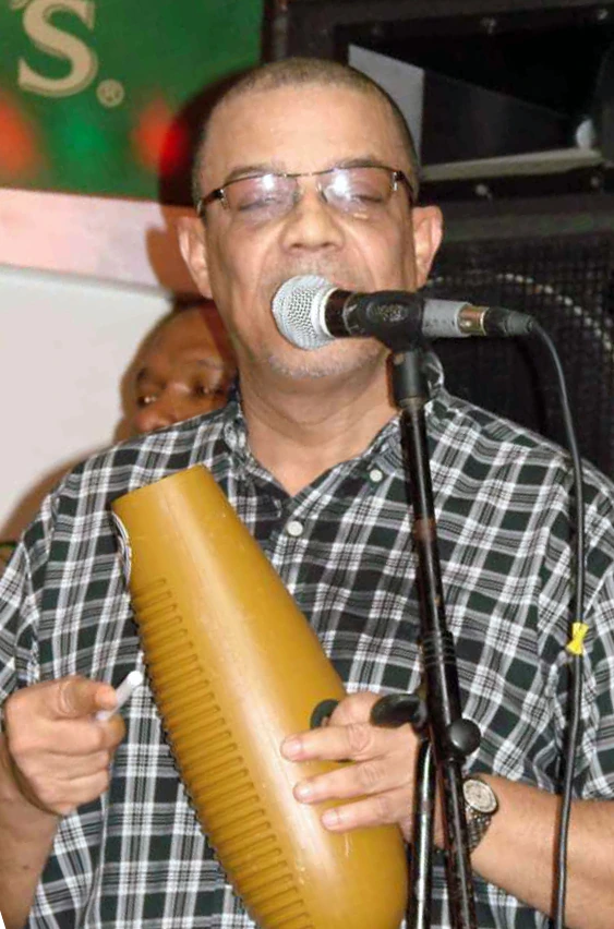 Fernando Varela performing with a microphone and güiro on stage