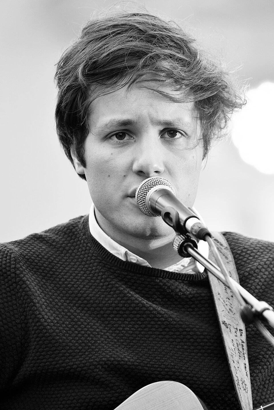 Black-and-white close-up photo of French singer-songwriter Vianney singing into a microphone on stage.