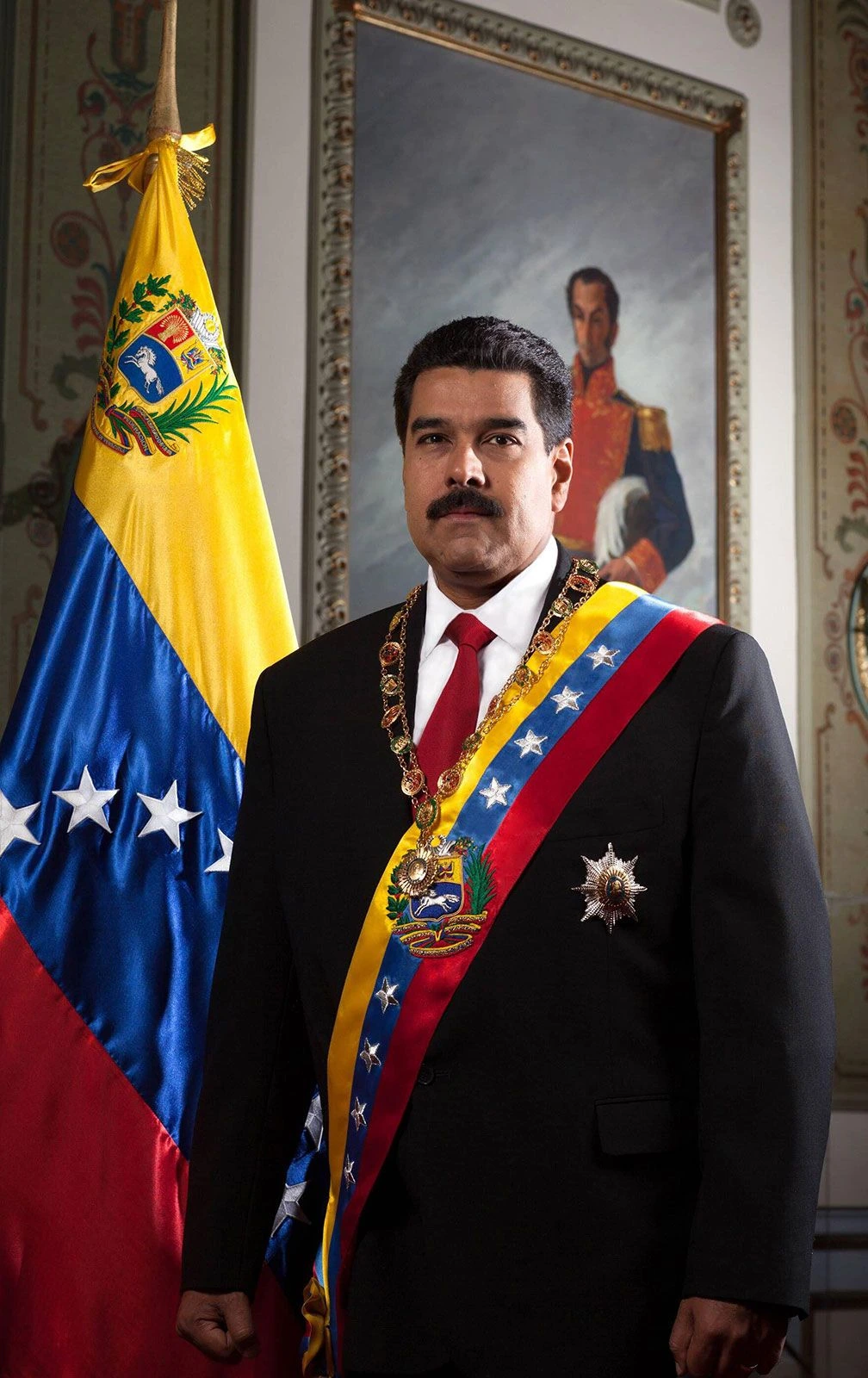 Nicolás Maduro in a formal portrait with Venezuelan flag and presidential sash