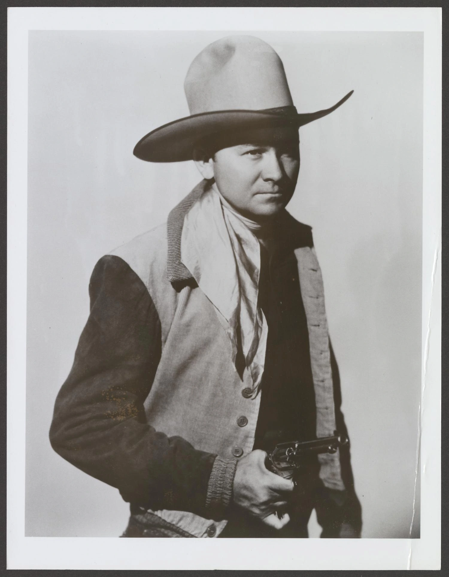 Tex Ritter portrait in western attire, holding a revolver and wearing a cowboy hat.