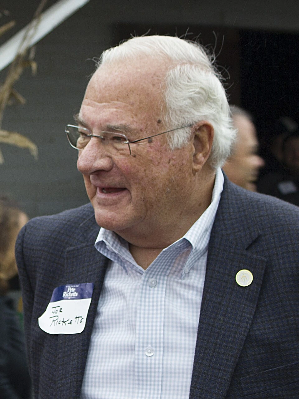 Joe Ricketts, founder of TD Ameritrade, in a candid outdoor photo wearing a blazer and name tag