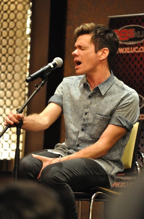 Nate Ruess singing into a microphone during a radio interview performance