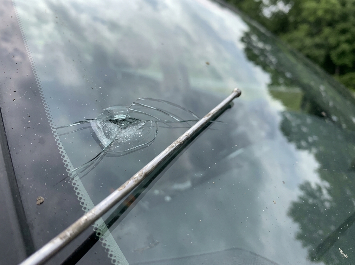 Windshield damage from a glancing impact showing a chip and shallow crack pattern.