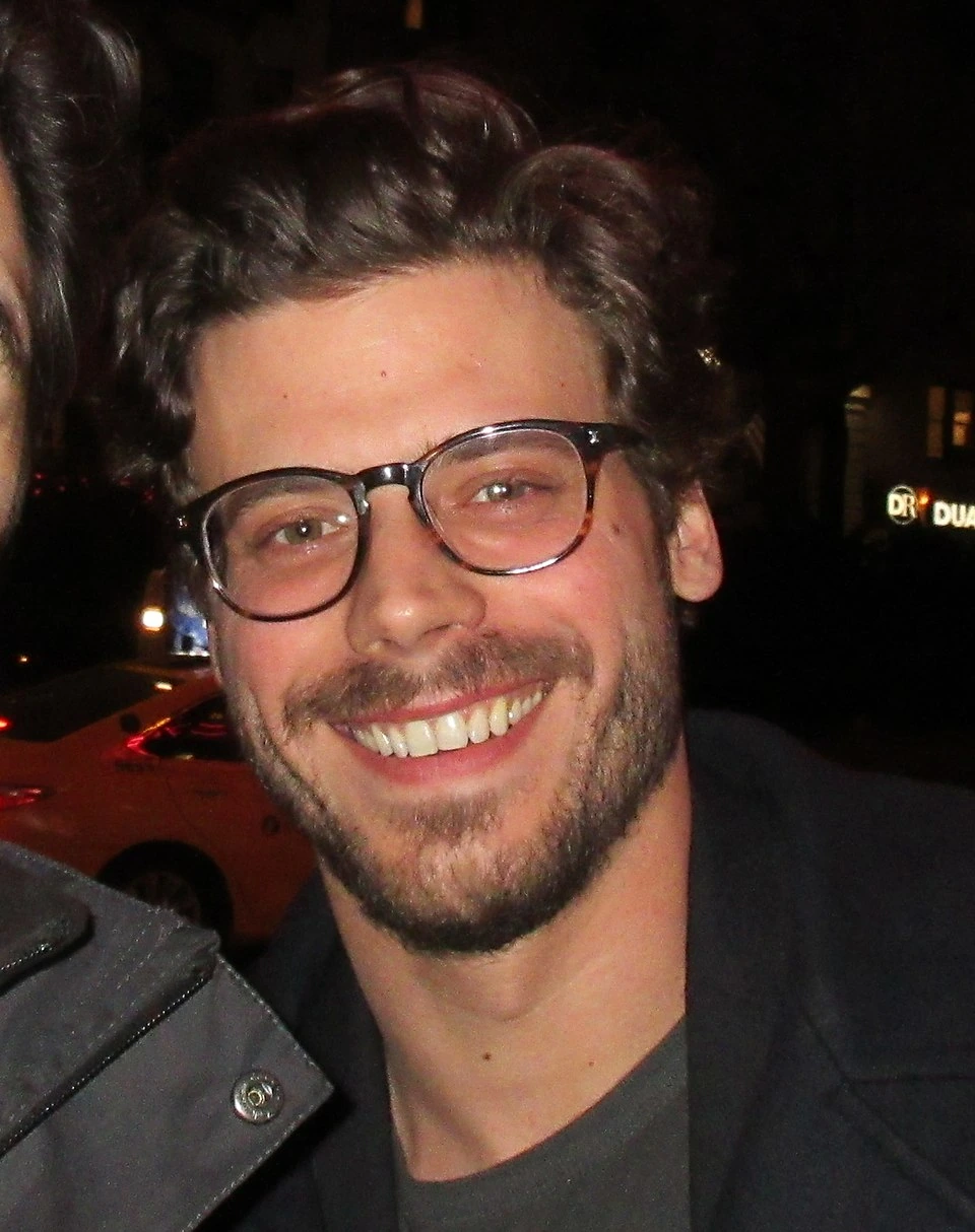 Close-up photo of François Arnaud smiling at an event at night.