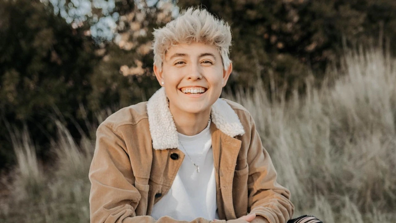 Mattie Westbrouck smiling outdoors in a casual portrait, wearing a tan jacket with a blurred natural background.