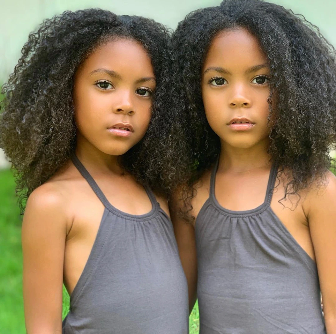 The McClure twins posing together outdoors in matching outfits
