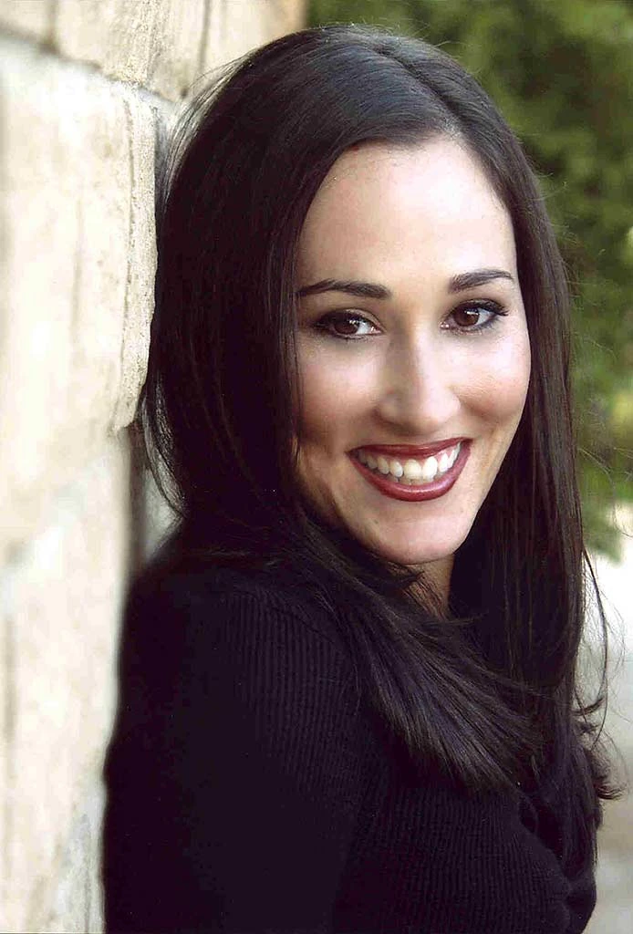 Portrait photo of actress Meredith Eaton smiling outdoors beside a stone wall