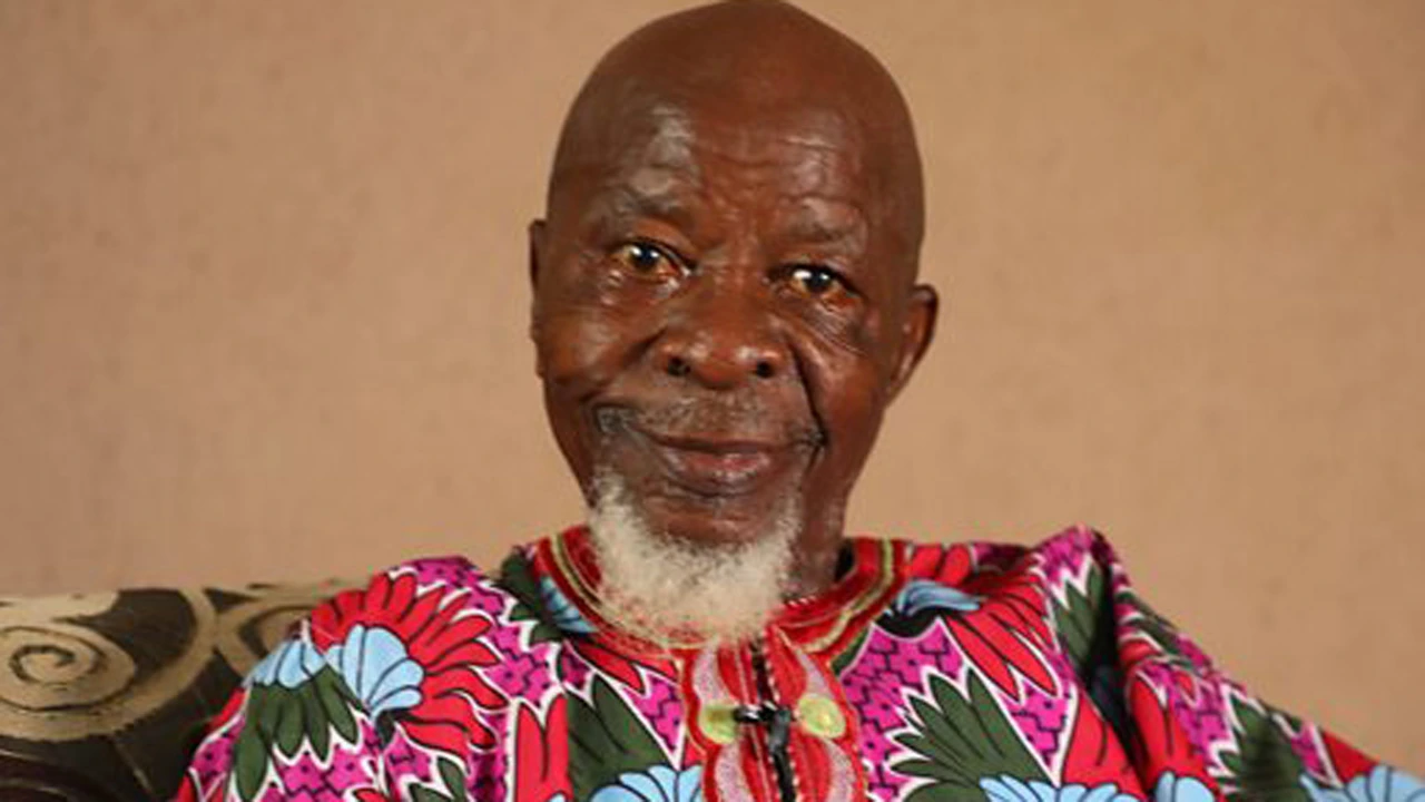 Portrait of Charles Olumo (Alhaji Abdulsalam Sanyaolu), Nigerian Yoruba actor, seated indoors in a colorful patterned ou