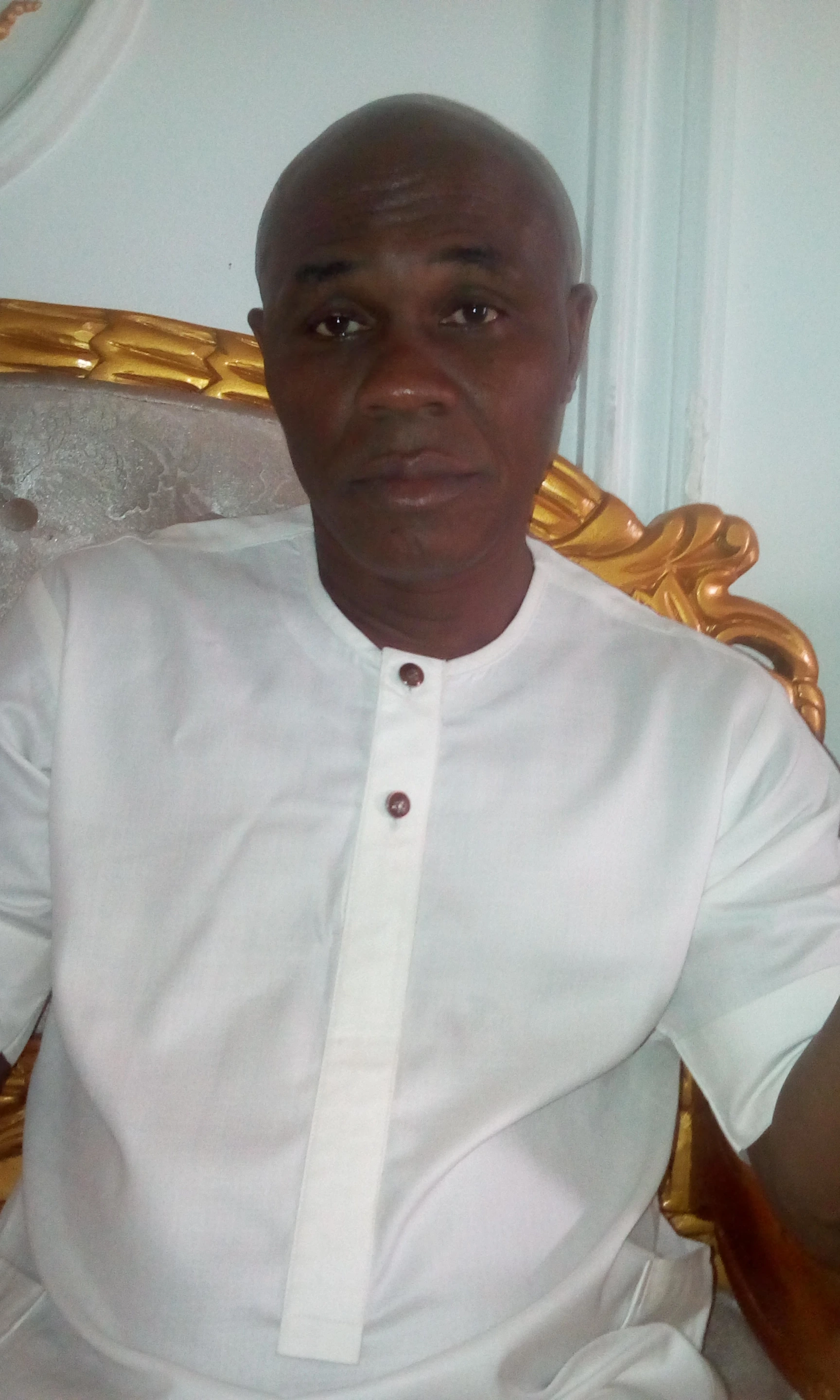 Portrait photo of Charles Ahize Ugochukwu in a white outfit, seated indoors