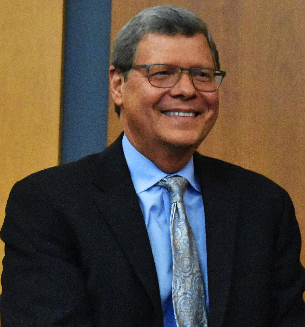 Portrait of Charlie Sykes smiling in a suit and tie