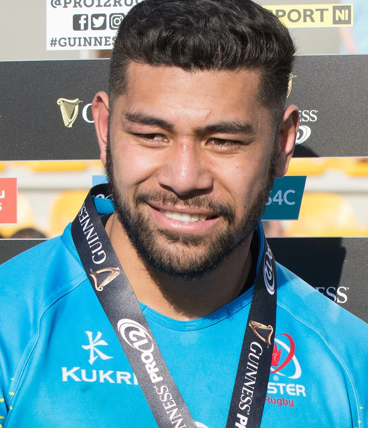 Charles Piutau portrait in a blue rugby jersey at a presentation backdrop