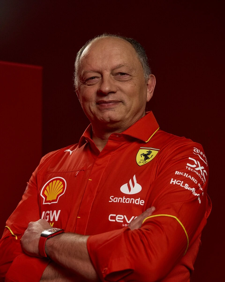Frédéric Vasseur in a Ferrari team shirt, posed with arms crossed against a red background.