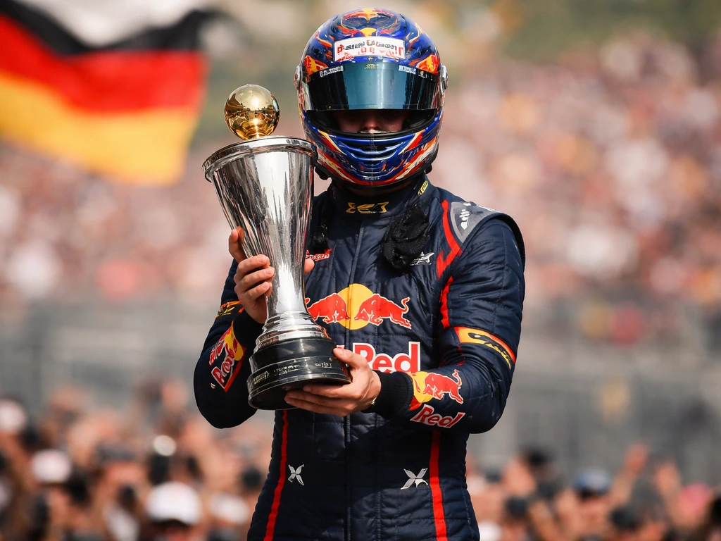 Anonymous helmeted F1 driver holding a championship trophy on a podium with blurred flags in the background