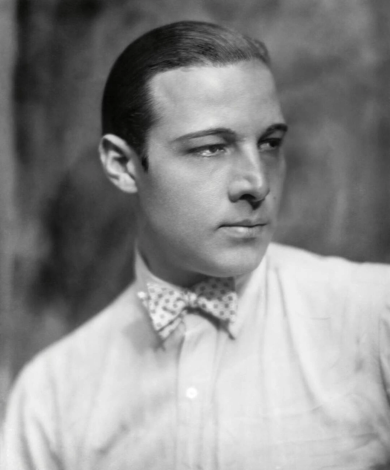 Black-and-white portrait of Rudolph Valentino in a bow tie and light shirt