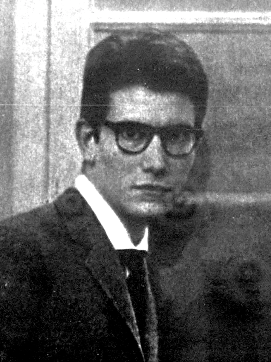 Black-and-white portrait photo of Yves Saint Laurent in 1961, wearing glasses and a suit