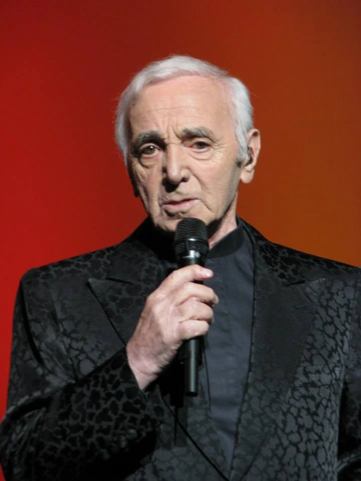 Charles Aznavour performing on stage with a microphone