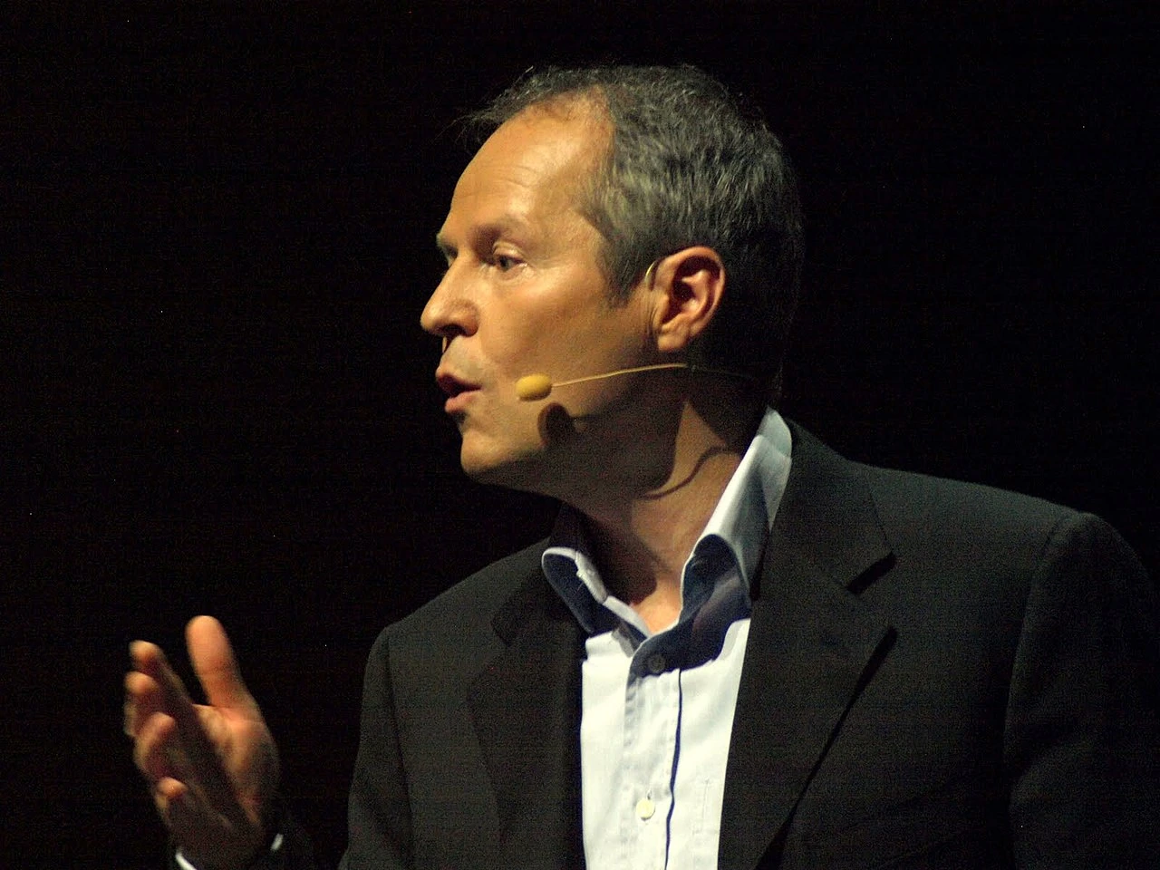 Yves Guillemot speaking on stage at a conference, wearing a headset microphone