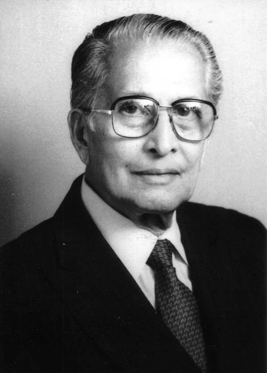Black-and-white portrait of a man wearing glasses, suit, and tie