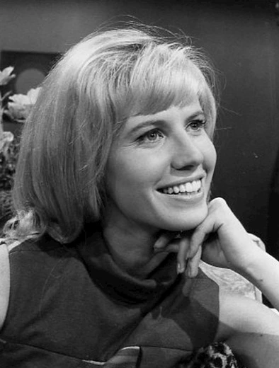 Black-and-white portrait photo of actress Leslie Charleson smiling and resting her chin on her hand.