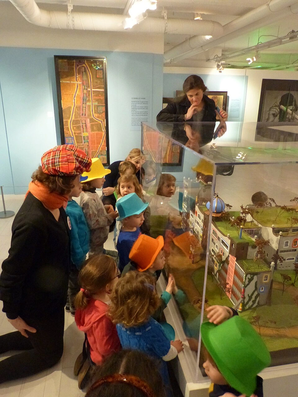 Des enfants visitent une exposition au Musée en Herbe à Paris, devant une maquette sous vitrine.