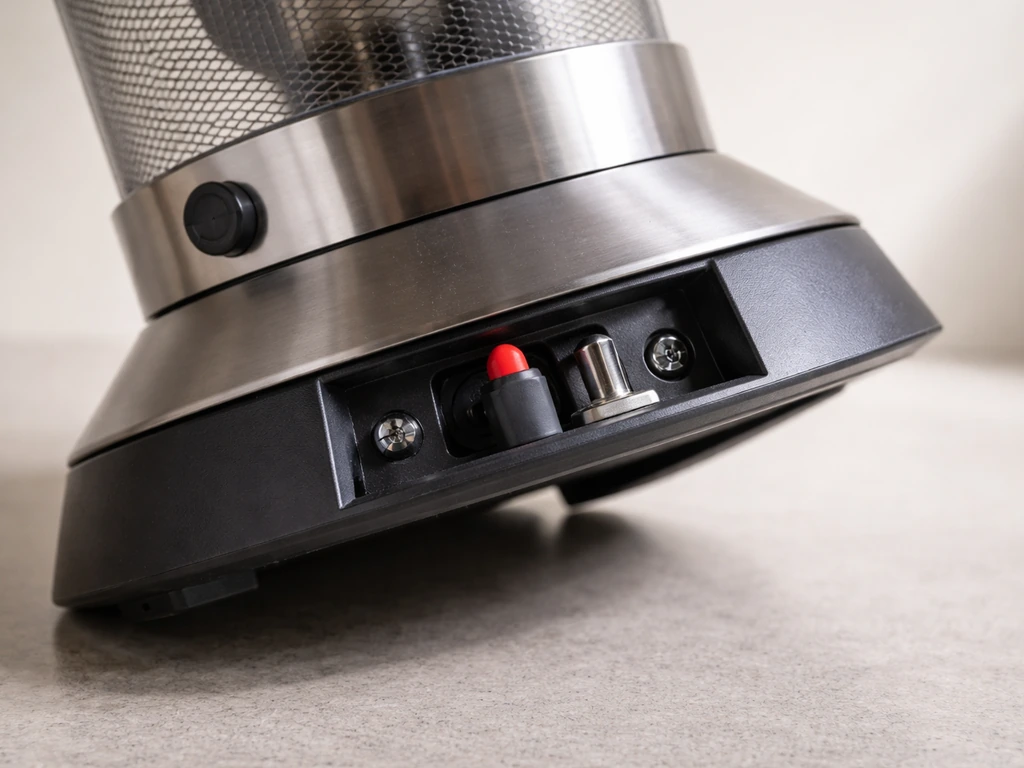 Close-up of a propane tabletop heater’s tip-over and flame-out safety mechanism with base slightly tilted