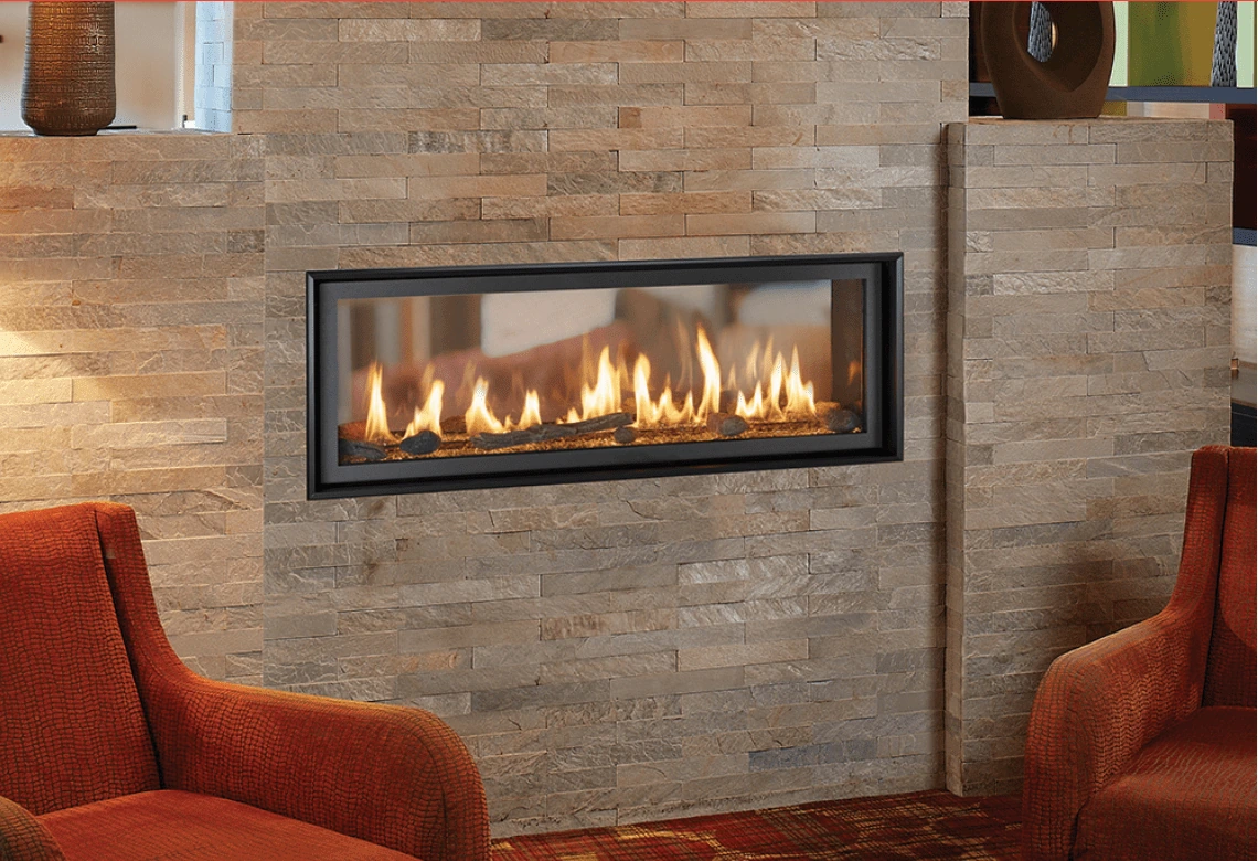 Showroom fireplace display with a lit gas fireplace set into a stone wall, flanked by upholstered chairs.