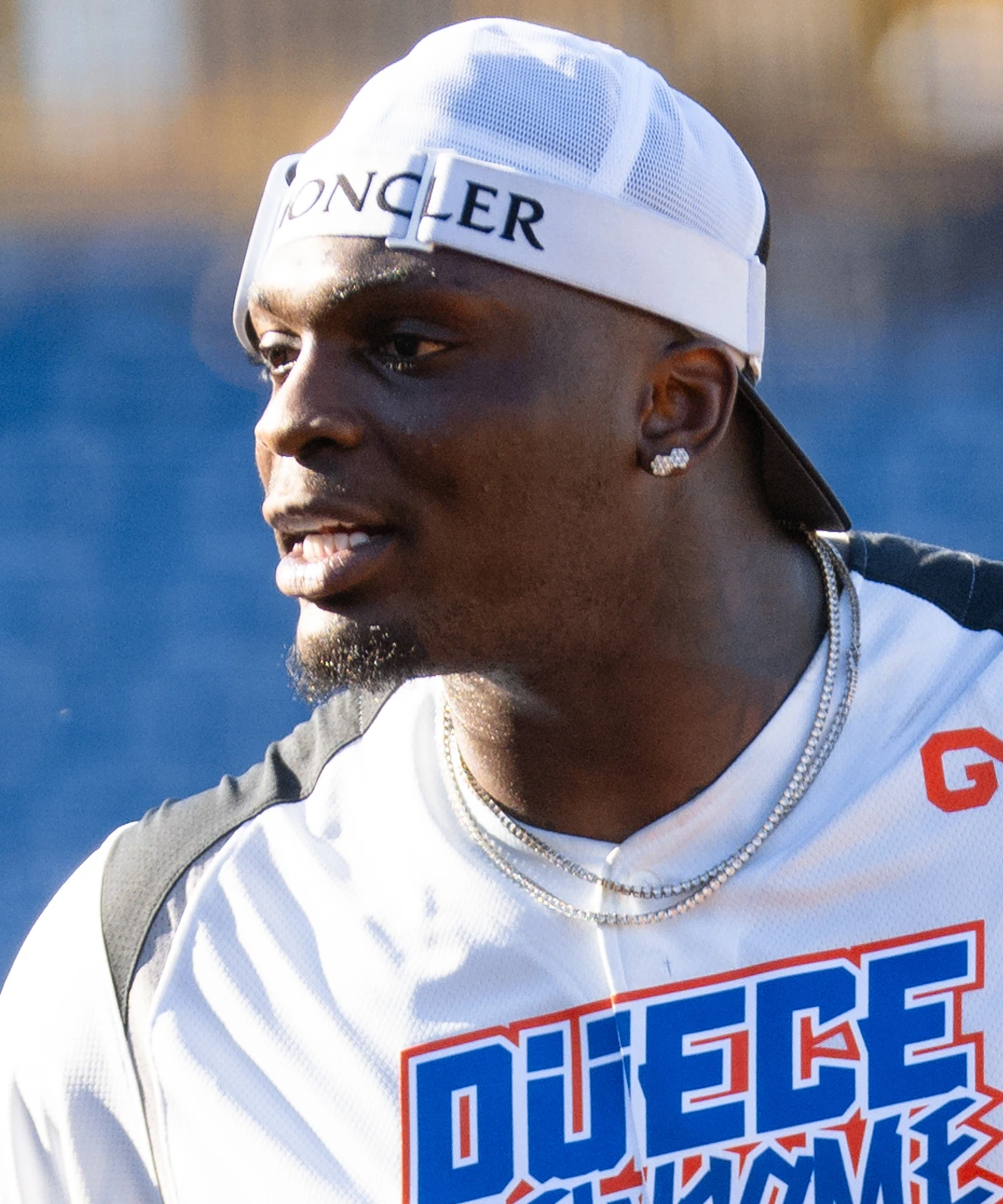 Perrion Winfrey in a white cap and athletic shirt outdoors at a football event.
