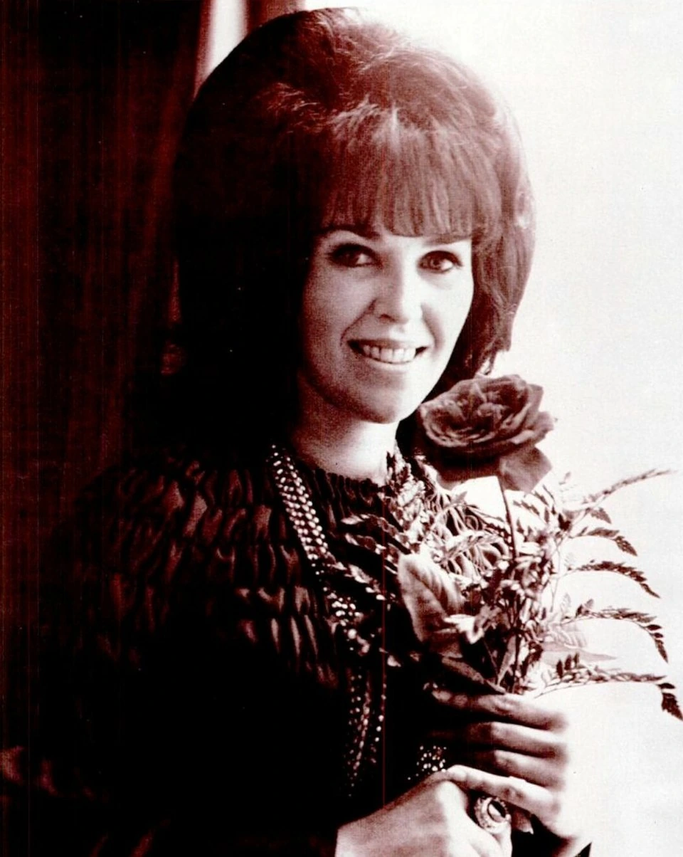 Wanda Jackson smiling and holding flowers in a portrait photo