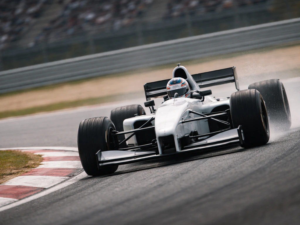British F1-era racing driver driving a late-1990s style open-wheel car on a racetrack